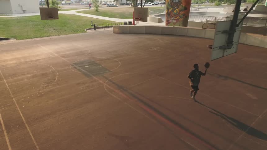 Man plays basketball alone in pavilion