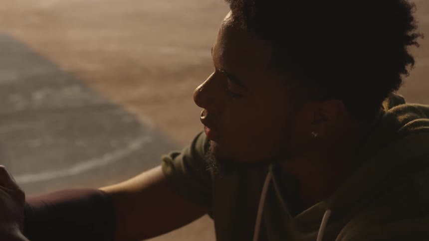A black man sitting outside on concrete
