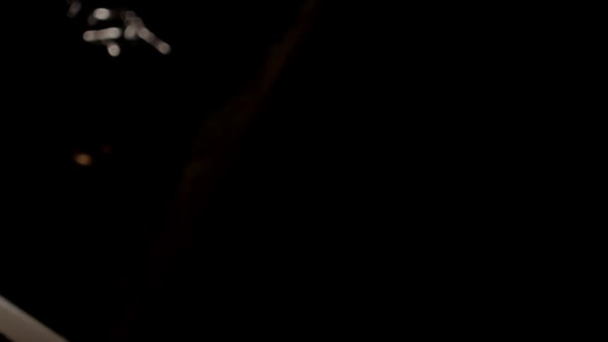 A view of a camera lens turning into focus before the view cuts away to four burning white candles