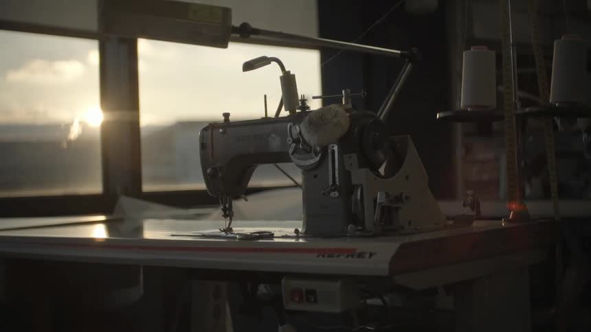 An industrial sewing machine rests on a large tabletop