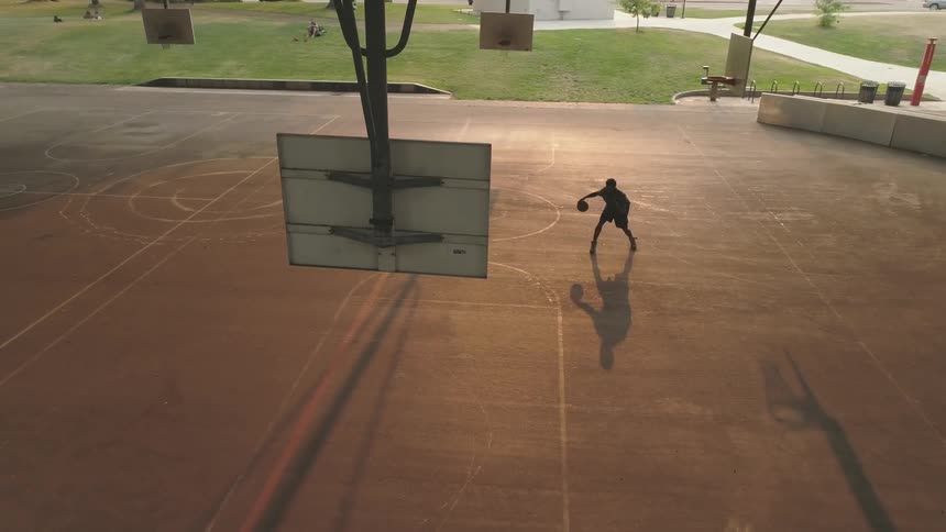 A man is dribbling a basketball on the court alone