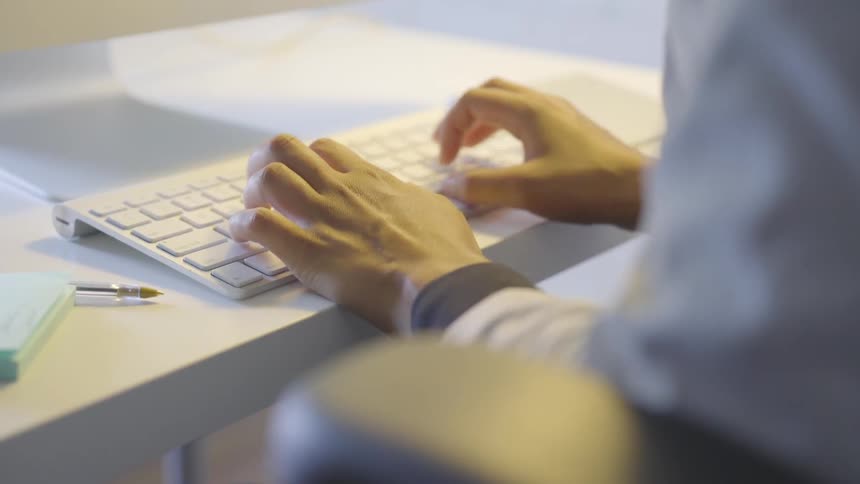 Man sitting at a desk typing on a keyboard