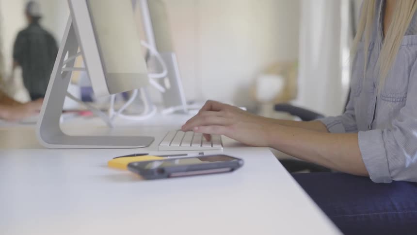 Blonde woman types on keyboard in the office during daylight