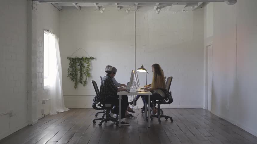 People working around a table on their computers in a large room