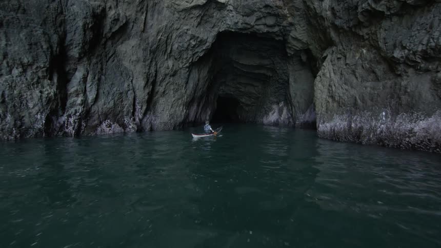 A man kayaks towards a magical hidden sea cave on the coast