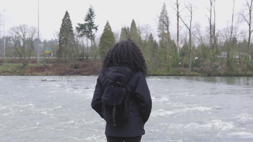 A young woman looks across the water