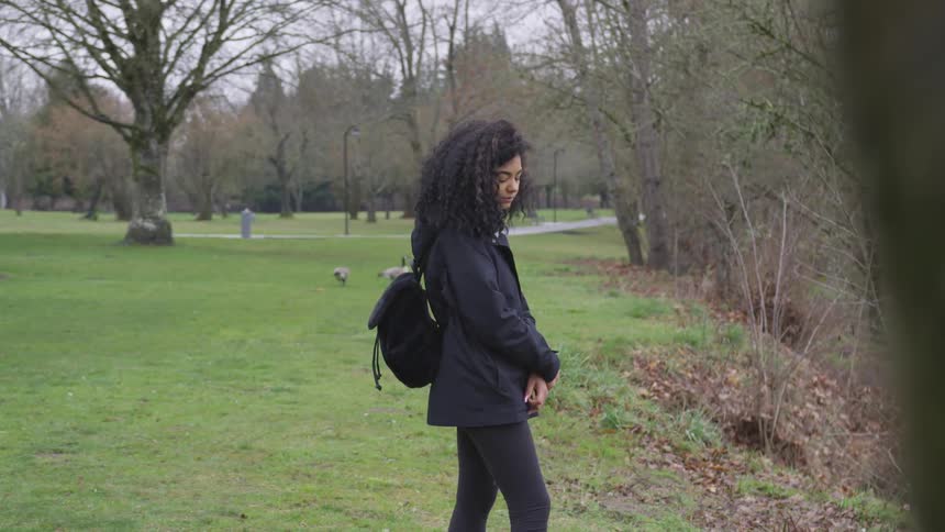 Woman stands in park with geese in background