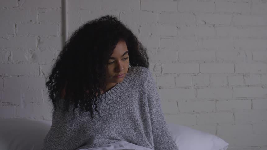 Woman sitting on bed looking down