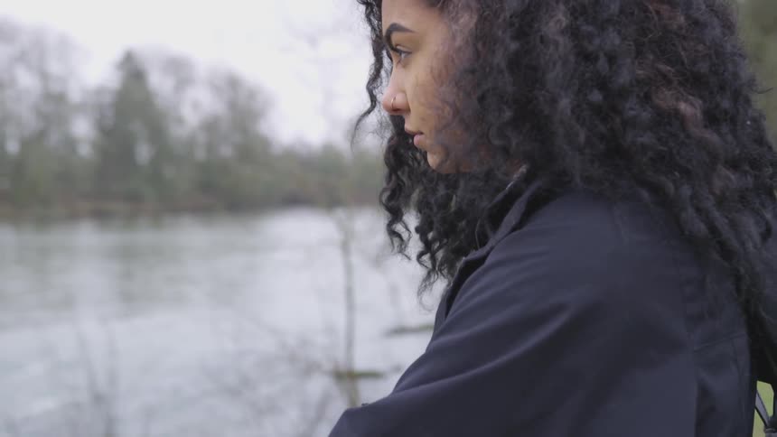 A black woman with a nose ring looks out over a lake