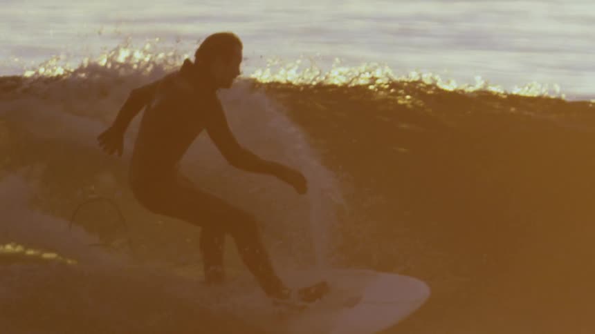 Slowmotion shot at sunset as a Man surf on backlit waves