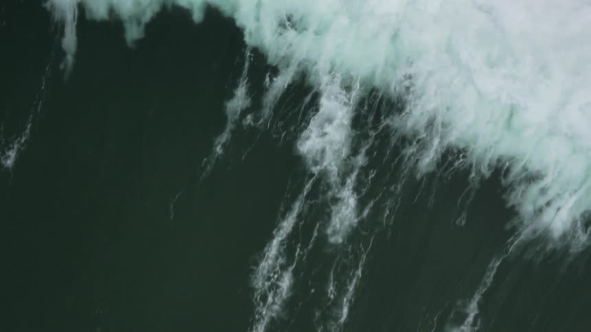 Aerial shot of a man surfing a small wave on his orange surfboard