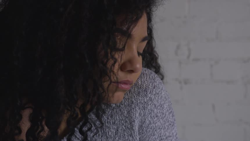 Woman sitting in a room looking down