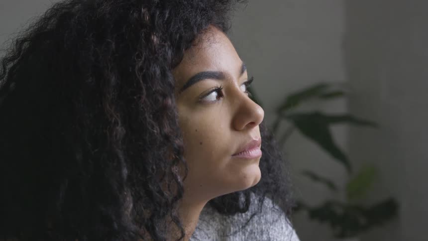 Young woman blinks her eyes and looks out a window