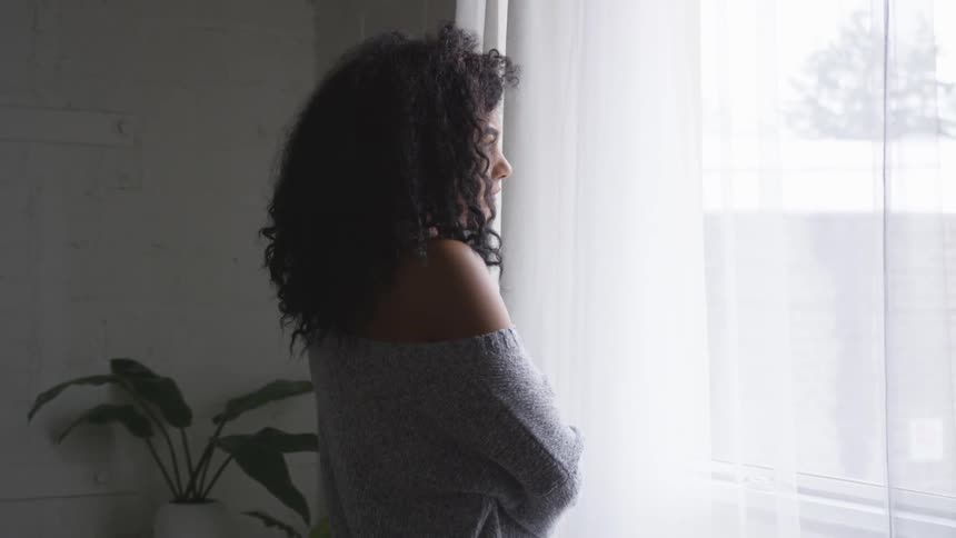 A young woman stares out of a window