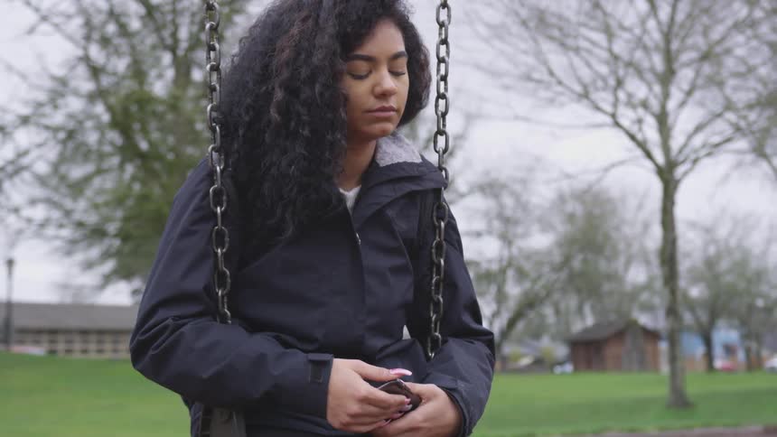 A young black girl sits on a swing