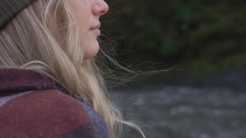 A young woman with a nose ring and blonde hair is by a river