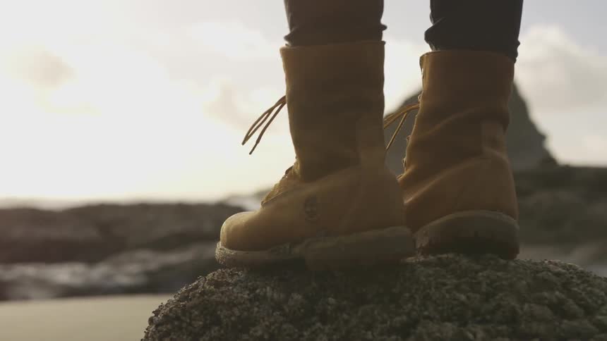 Person stands on rocks at beach