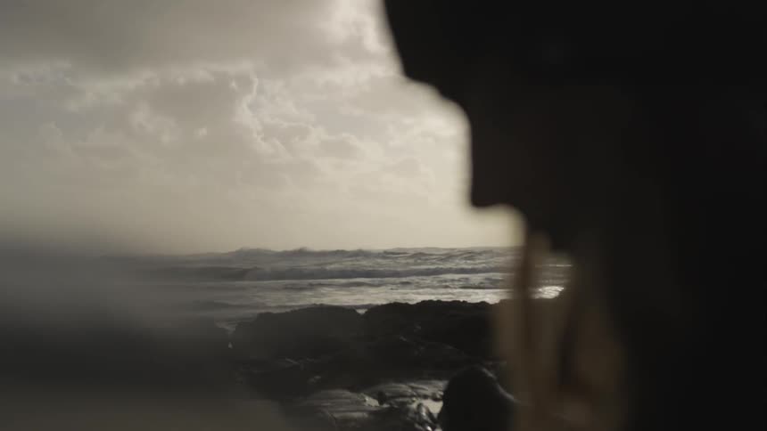 A female head profile near rocks near a body of water