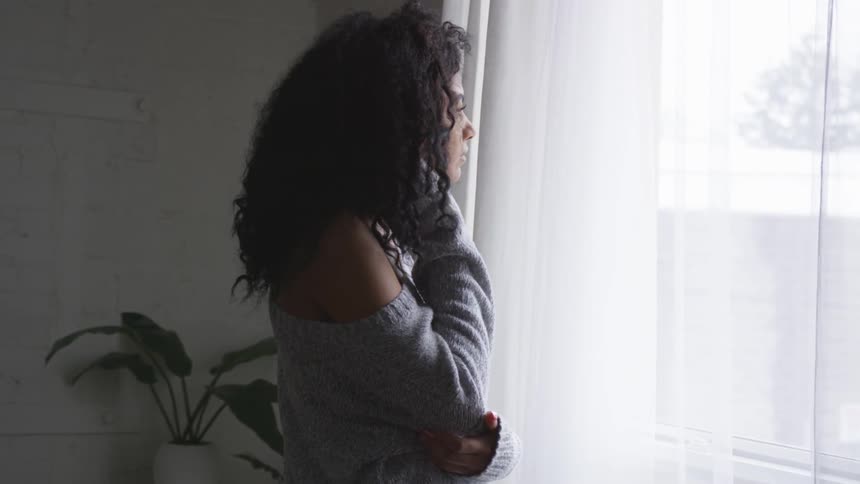 Woman stands looking out window