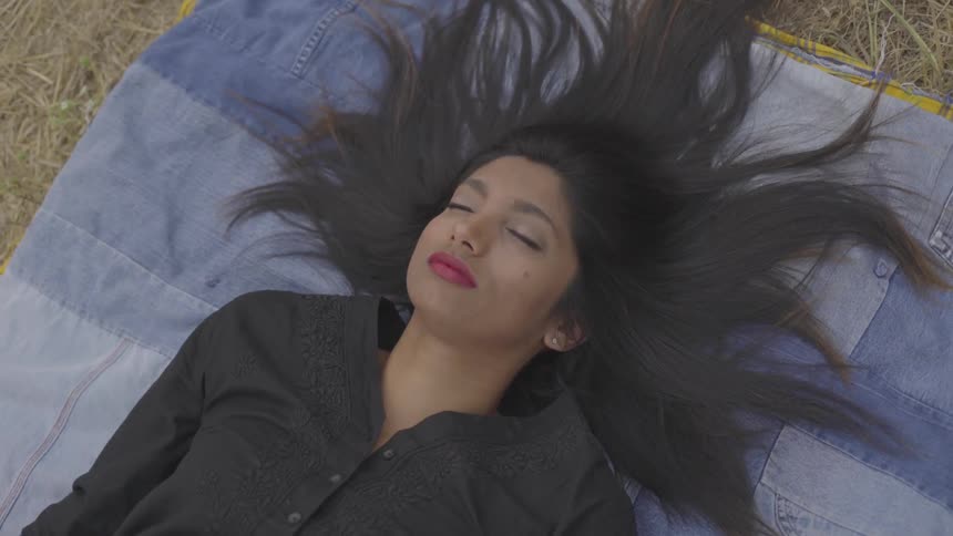 Woman lays on a blanket on the straw with her eyes closed