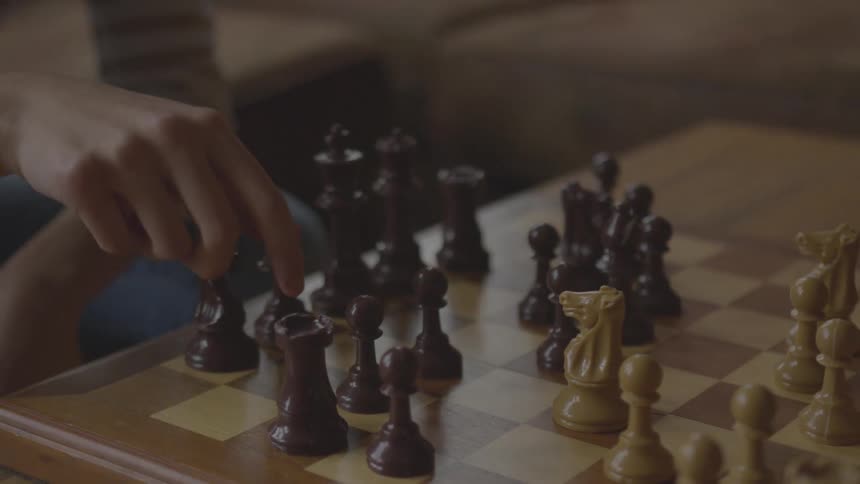 A person sitting at a chess table making a move