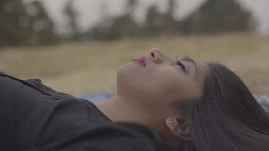 A woman opens and closes her eyes while laying on the ground