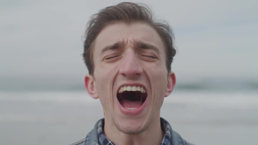 Male screaming loudly while standing near the beach