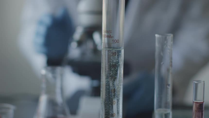 Scientist in a blue gloves works with a microscope