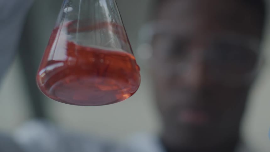 A man swirls a solution in a beaker