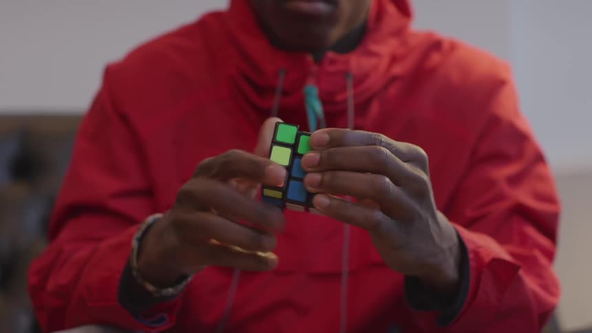 A black man quickly solving a Rubik's cube