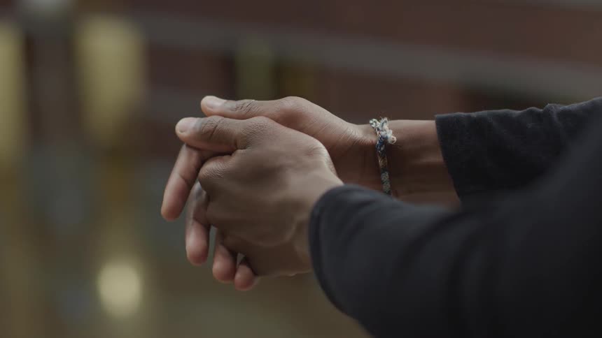 A woman in a dark long sleeved shirt clasps her hands together as she is pondering what she is looking at