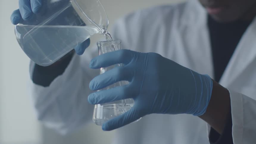 A scientist pours a liquid into a cylinder beaker