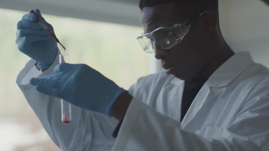 Black man pours the liquid from a pipette to a test tube