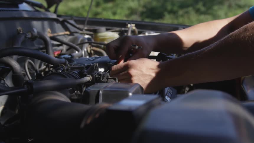 A person works on an engine on a sunny day
