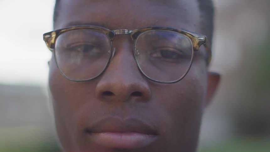 A black man with glasses blinks
