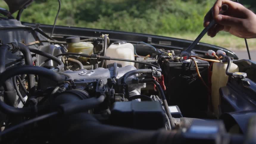 Man uses a wrench to work on the engine of his vehicle