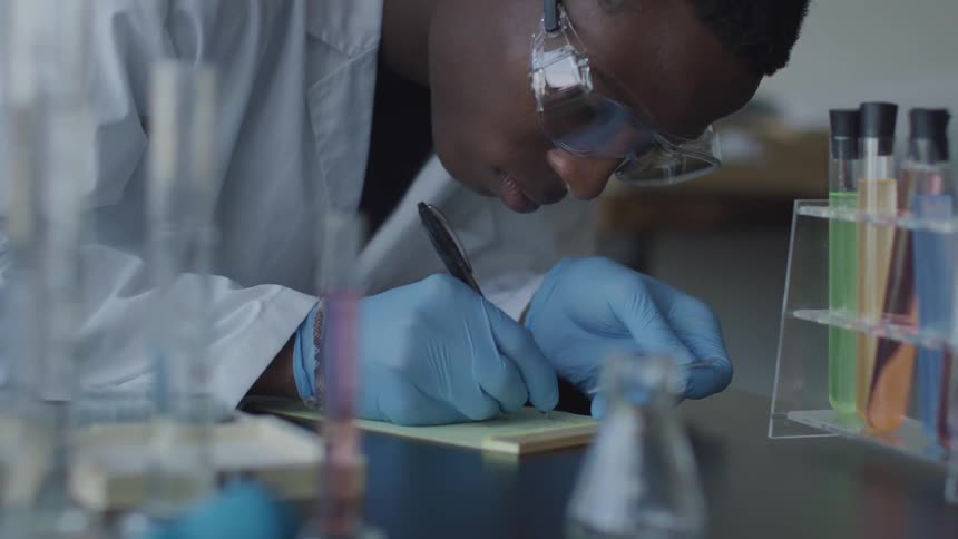 Man working in lab makes notes on notepad