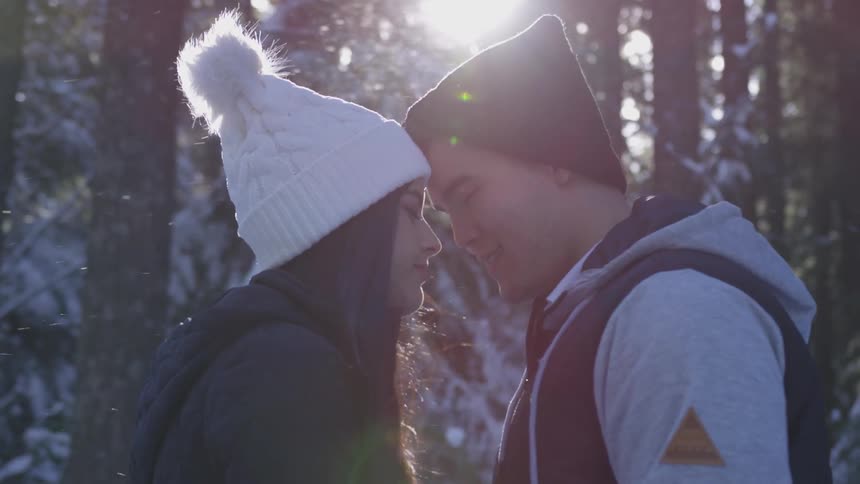 Couple touching foreheads while standing on a snowy forest