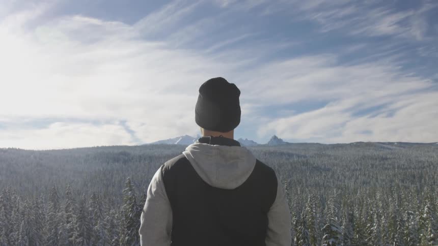A man outside staring at mountains