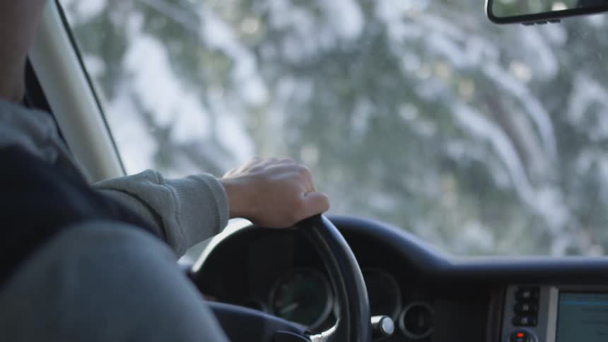 Man drives past snow covered trees