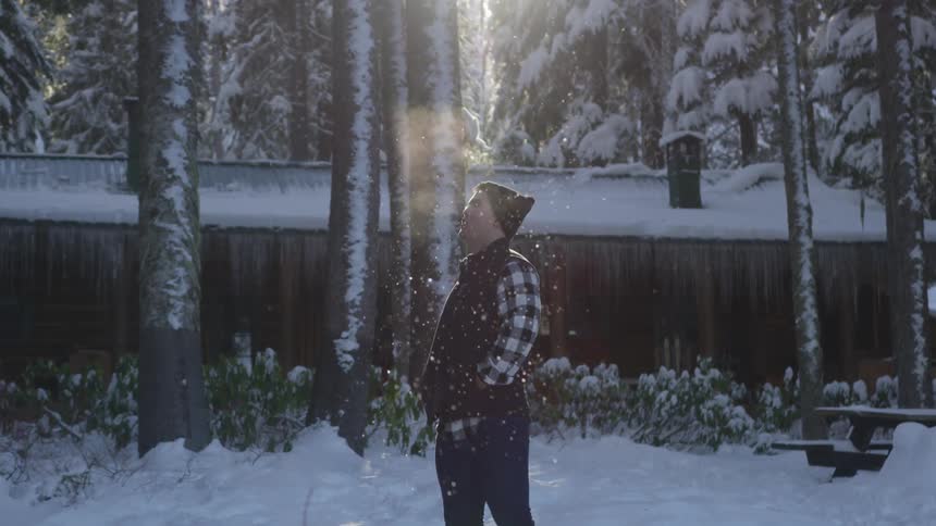 Man stands outside in yard while it snows