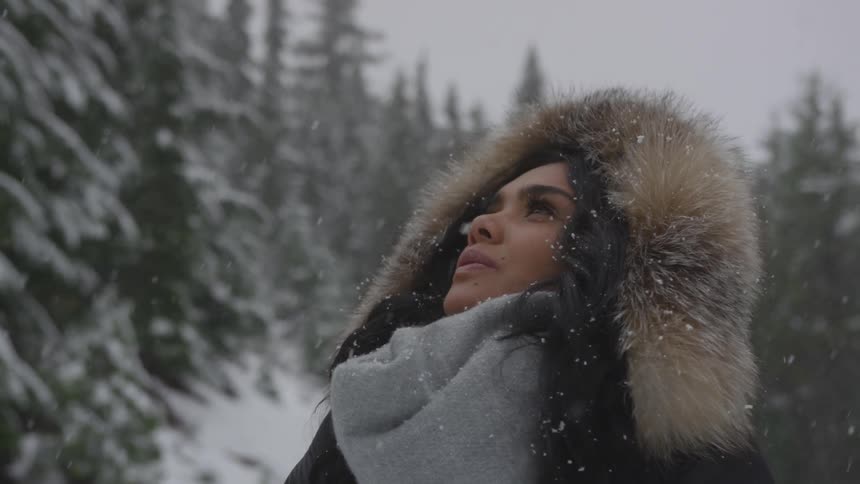 A woman is looking up while its snowing
