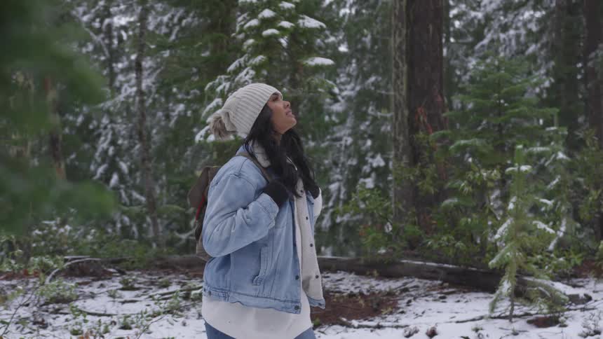 A young woman walks through a snowy forest