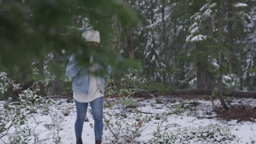 Woman walks through snow covered forest