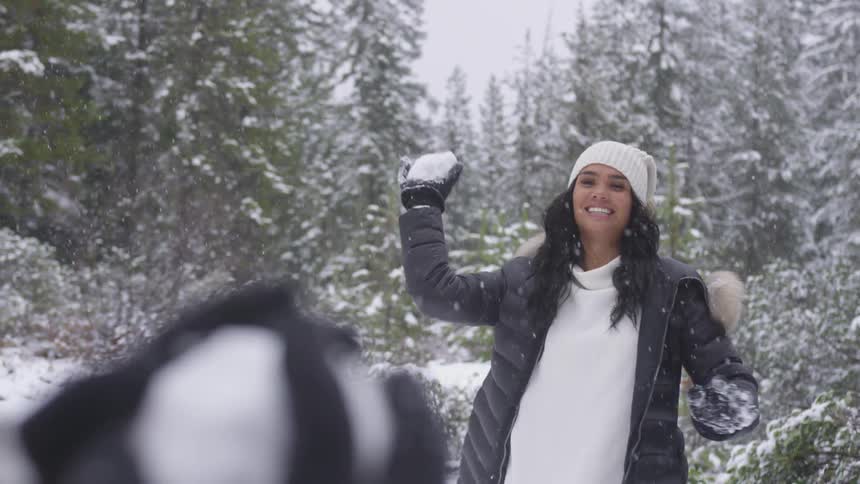 A young girl throws a snowball at her friend
