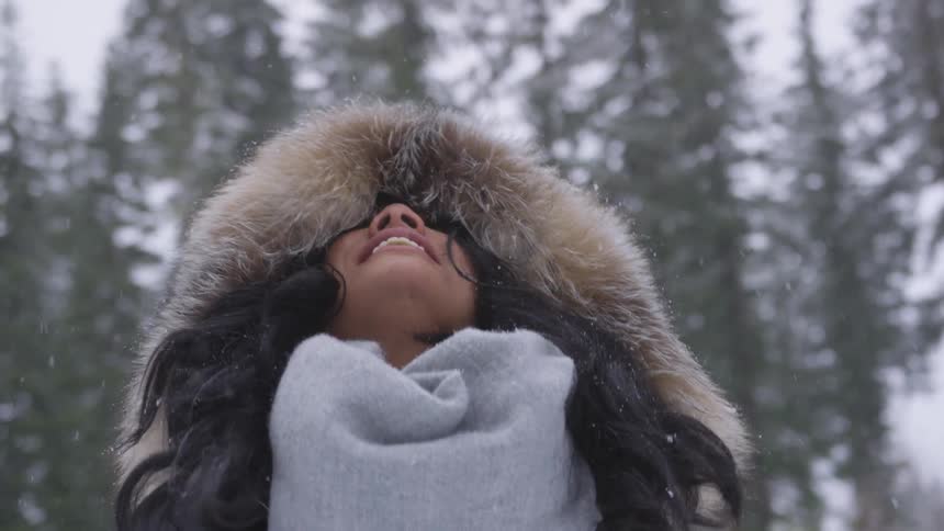 Smiling woman picking up snow and throwing it up
