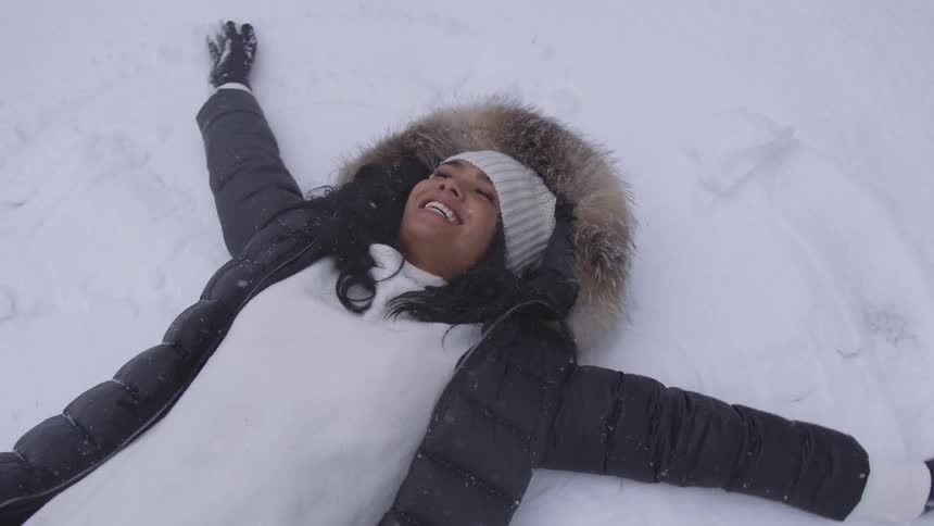 A woman makes snow angels in the snow