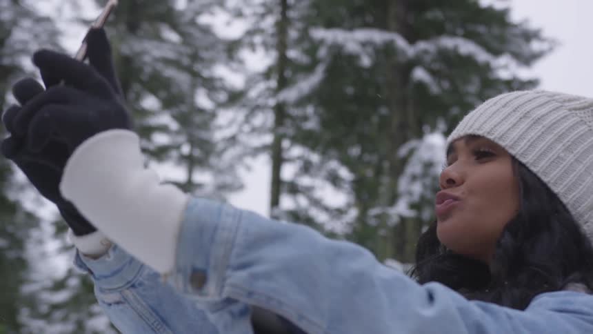 A woman takes a selfie while standing outside in the snow