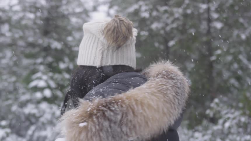 A woman laughing while dodging a snowball