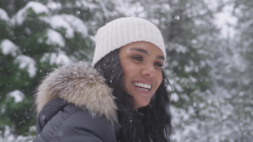 A woman throws a snowball as it snows